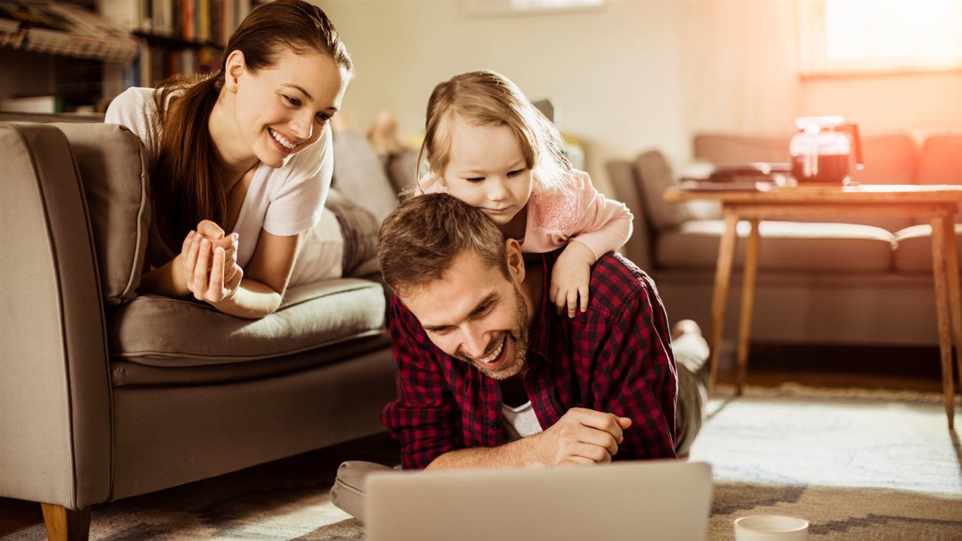 Família reunida olhando um notebook juntos, luz da janela