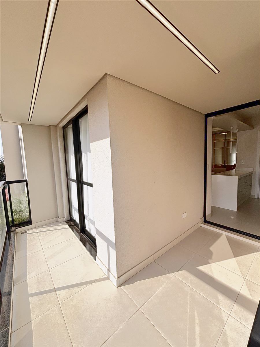 Sacada em L do apartamento decorado, com acesso pela cozinha e pela sala