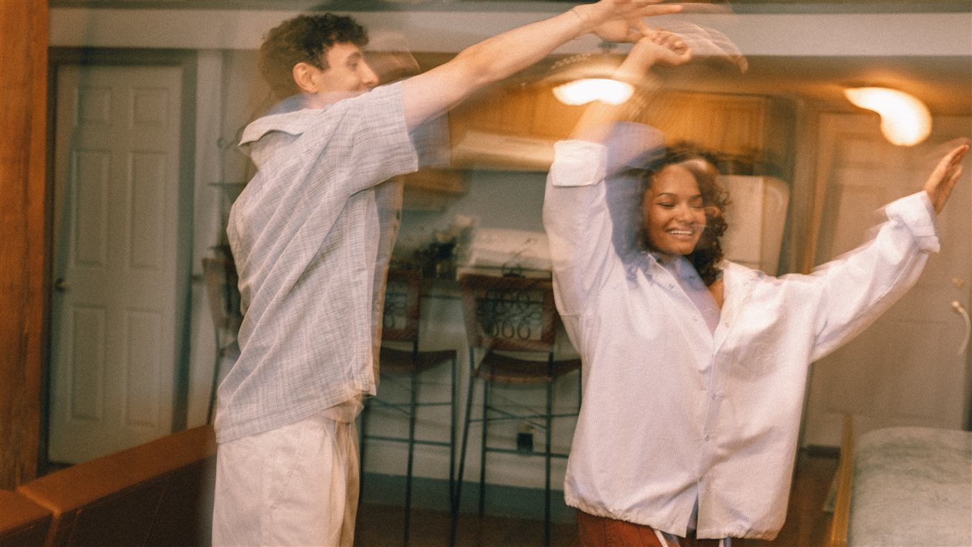 Casal dançando em casa, luz quente de fim de tarde