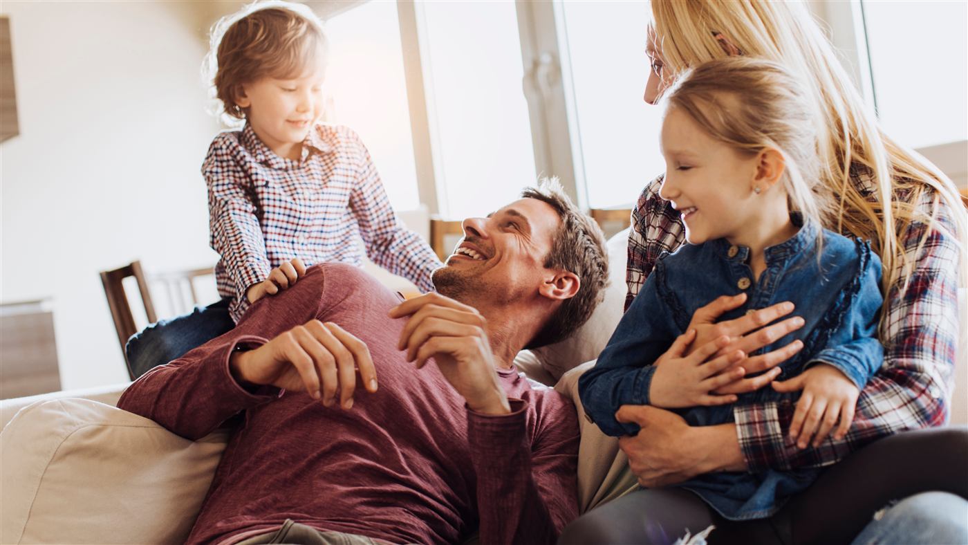 Família reunida no sofá, pai brincando com os filhos